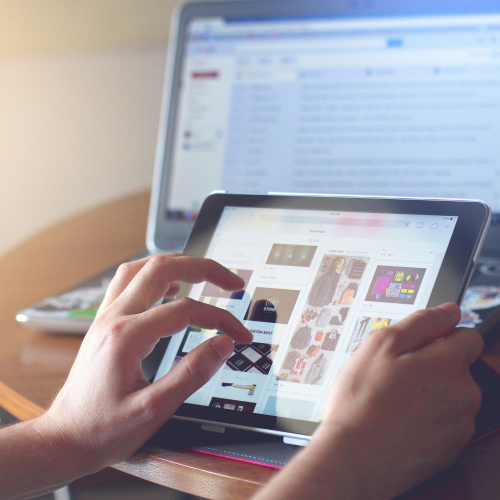 someone looking at tablet with laptop in background