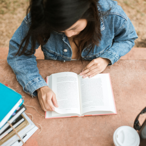 person reading a book at a table outdoors