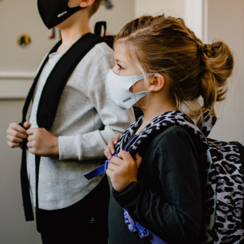 Pair of children wearing masks and backpacks