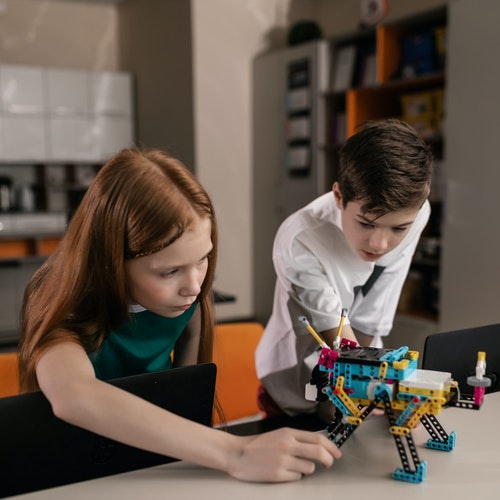 Two children making a LEGO robot.